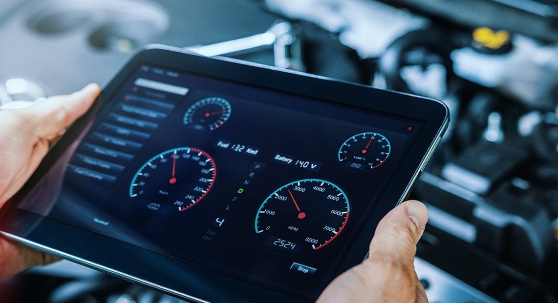 a hand holding a tablet with a screen showing the speedometers and gauges