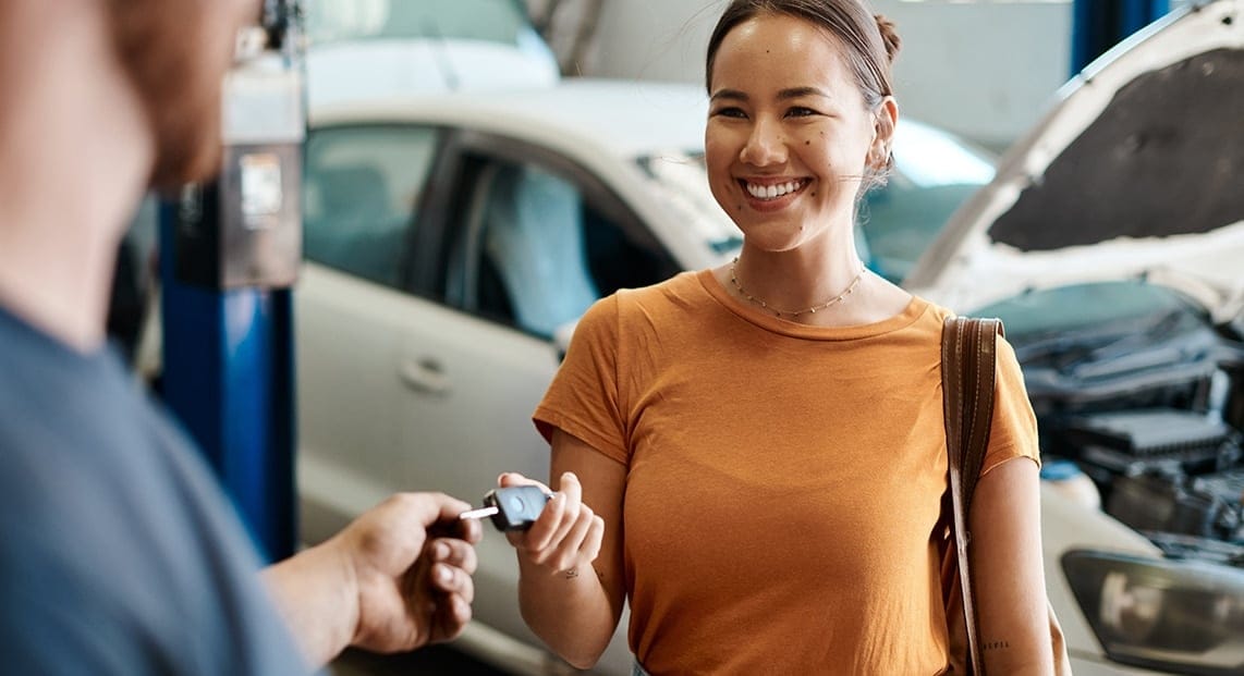 a woman smiling and holding a car key