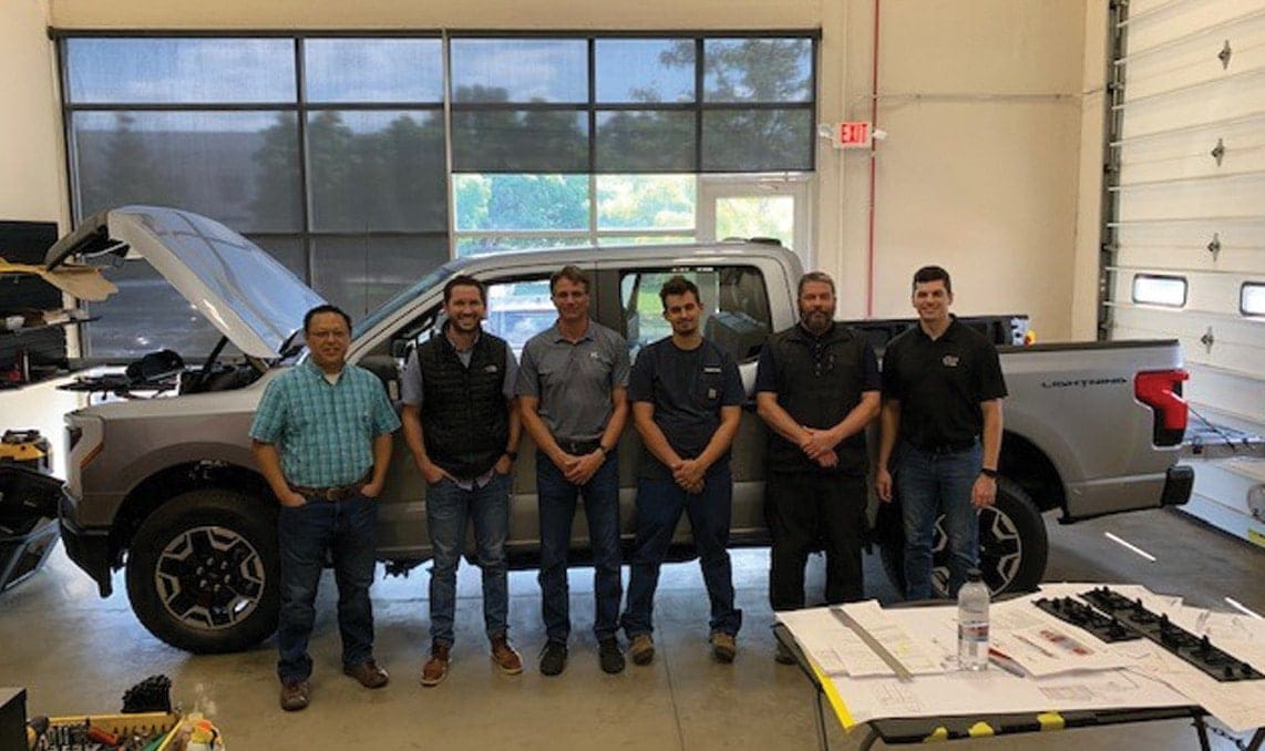 a group of men standing in front of a truck