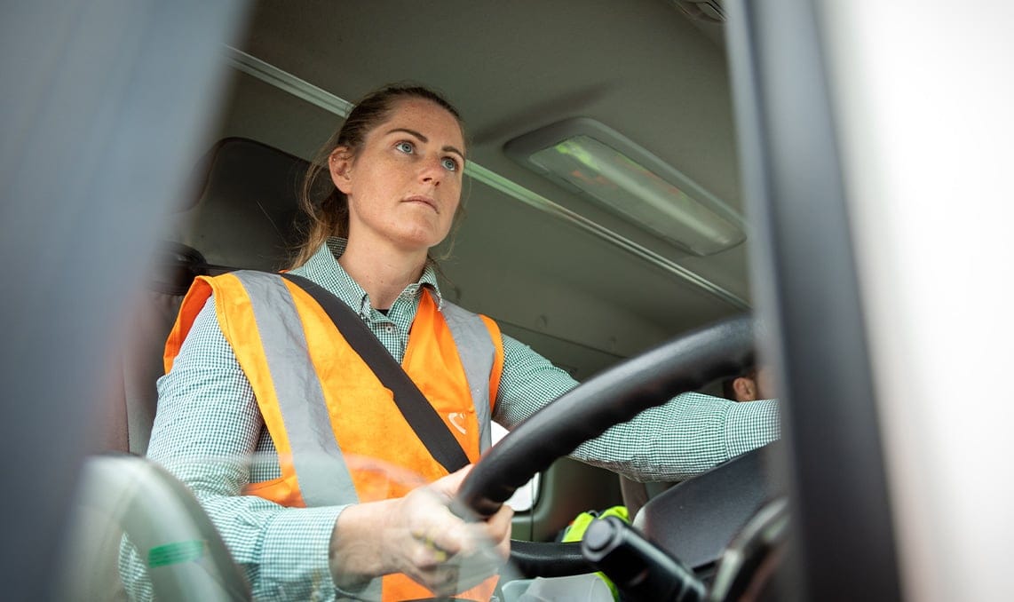 a woman in a safety vest driving a car