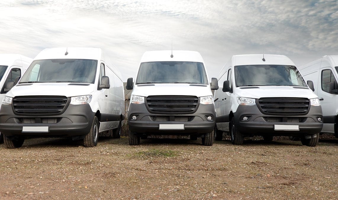 a group of white vans parked in a row