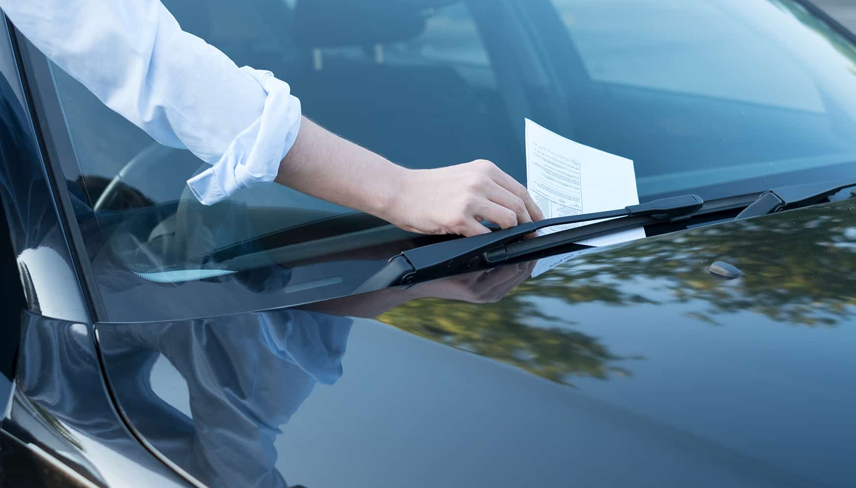 a person holding a paper on the windshield of a car