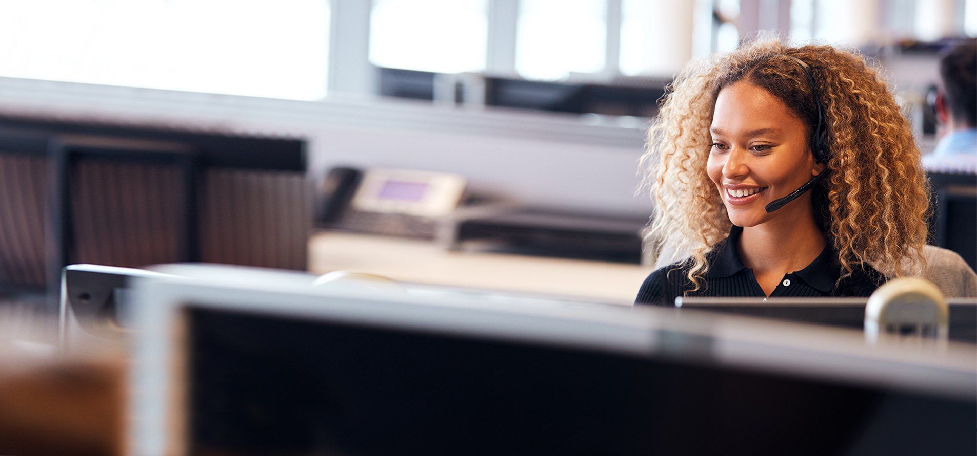 a woman talking at a desk on a headset