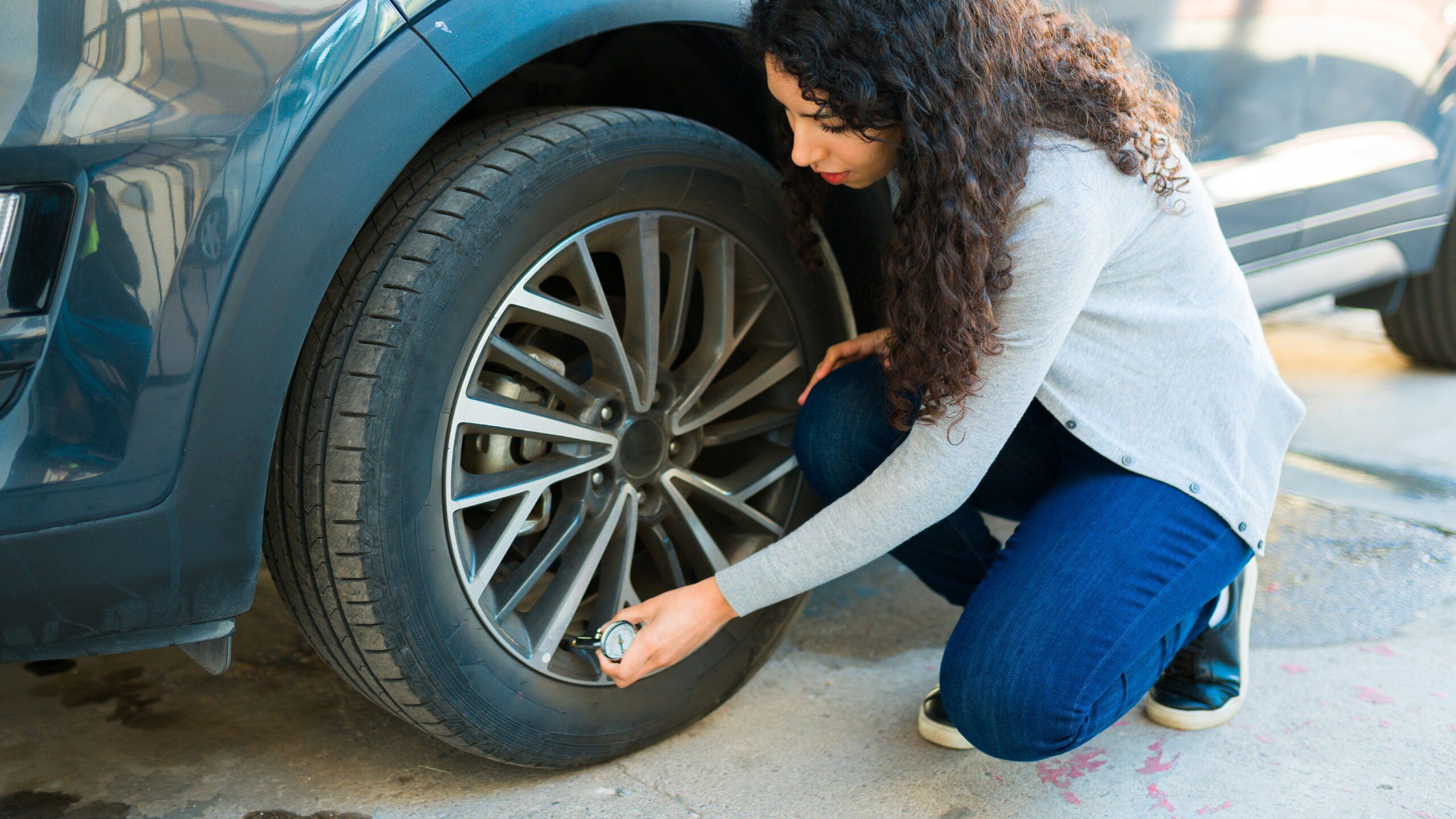 a woman checking the tire of a car