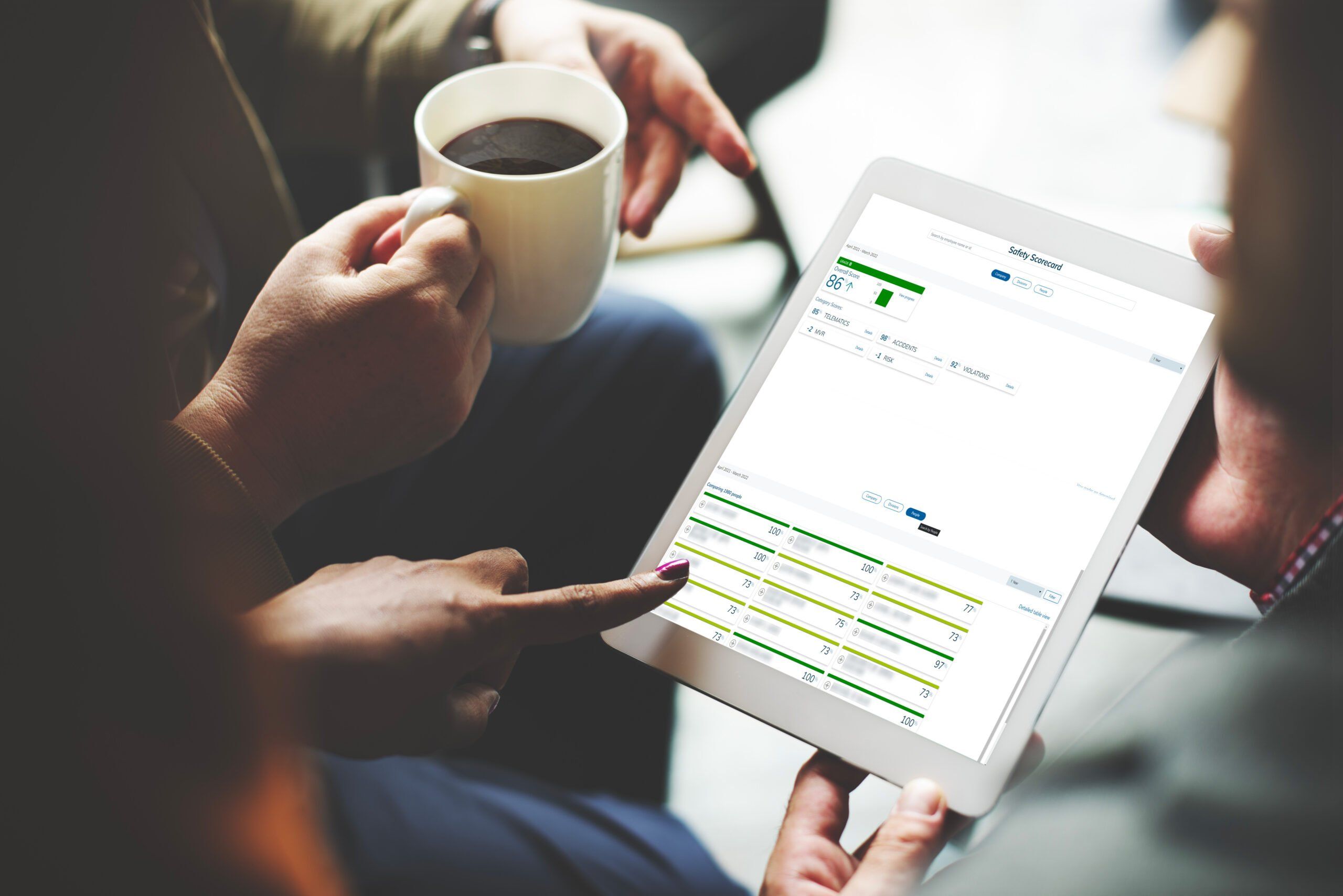 Man holding a cup of coffee while looking at data on the tablet