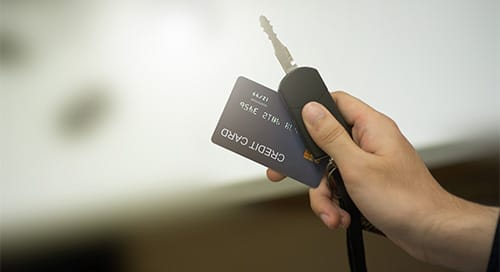a hand holding a key and a credit card