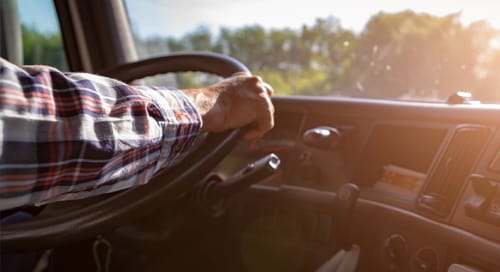 a hand on a steering wheel