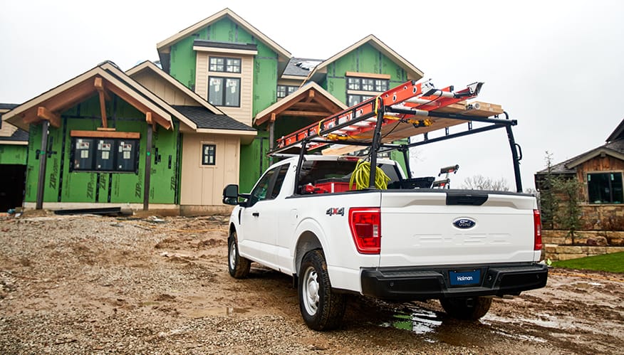 A white pickup truck with building materials on top at a construction site