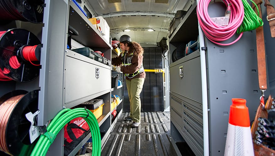 A utility worker in the back of an upfitted van