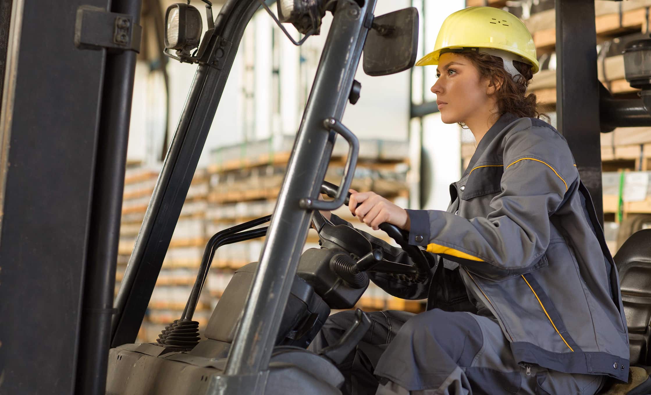 a woman in a hard hat driving a forklift