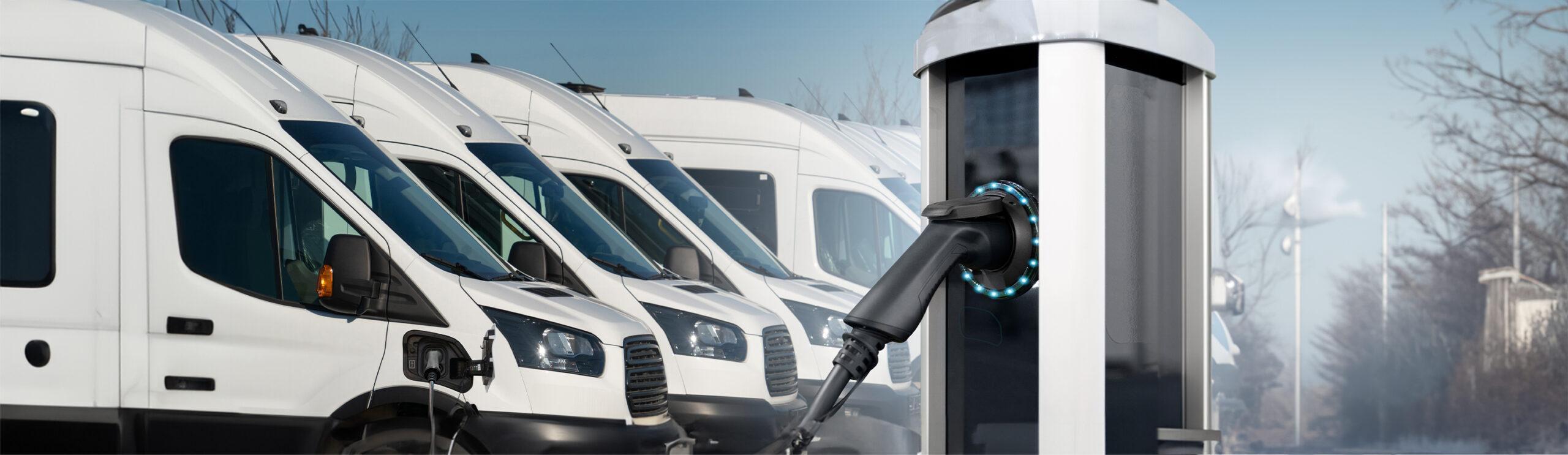 a hand holding a power cord next to a row of white trucks