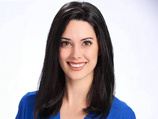 a woman with dark hair wearing a blue shirt 